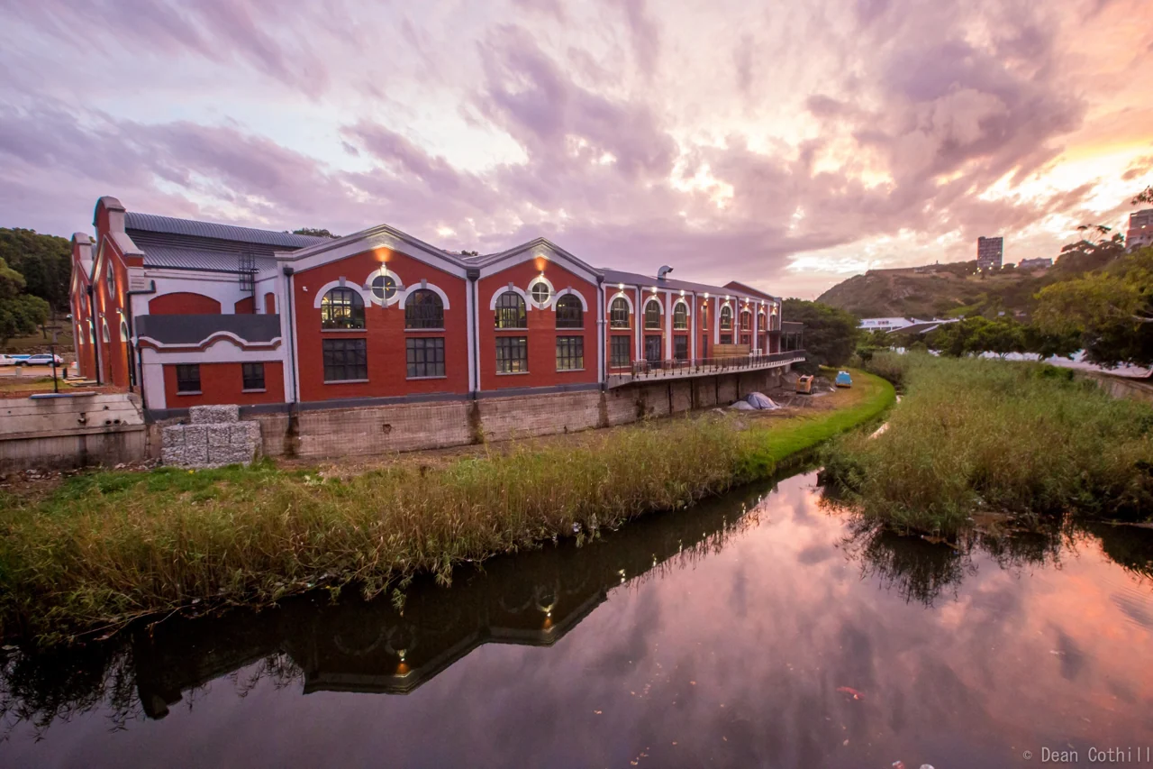 A red heritage building reflected in water in Gqeberha